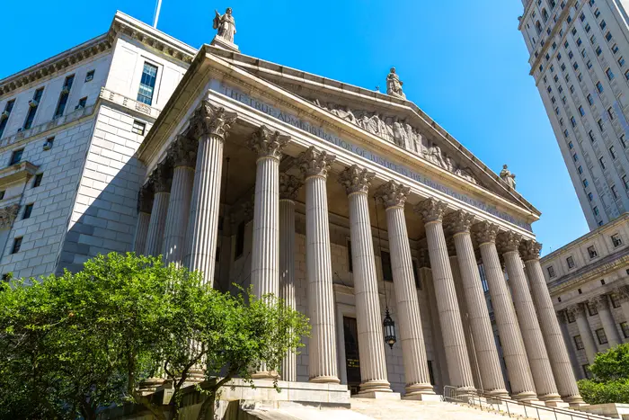 The exterior of the imposing New York Supreme Court building, with its pediment and pillars
